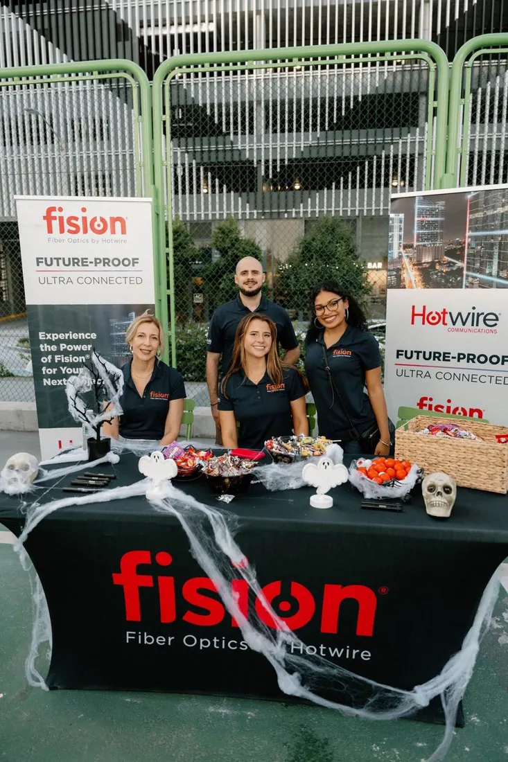 The Hotwire and Fision team at their decorated sponsor table in 2025