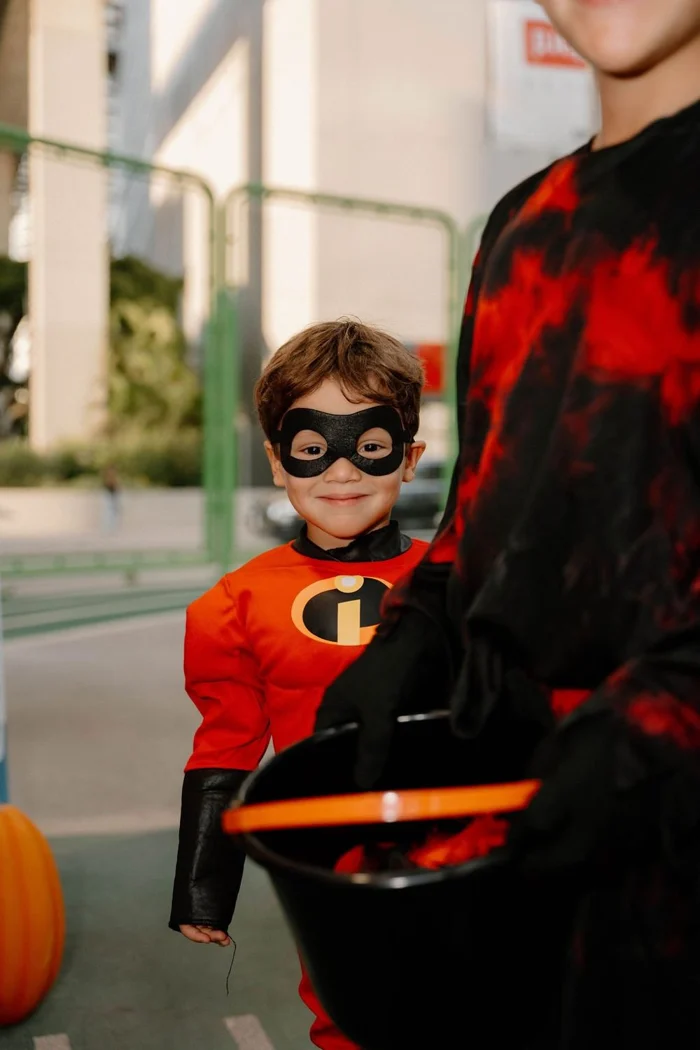 A child in a red superhero costume with a black eye mask